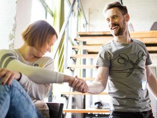 Photo of seated woman holding man’s hand