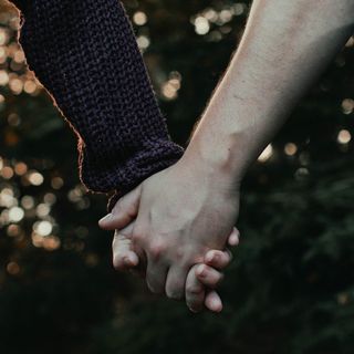 Two people’s hands holding one another.