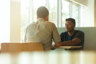 Two men sat at a desk talking