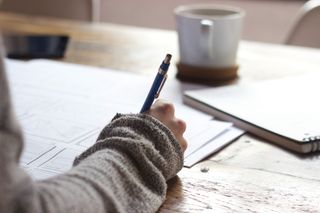 Photo of someone making notes in a notebook while sat at a desk.